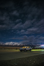 A cozy taxi parked by a scenic mountain road in Manali at sunrise.