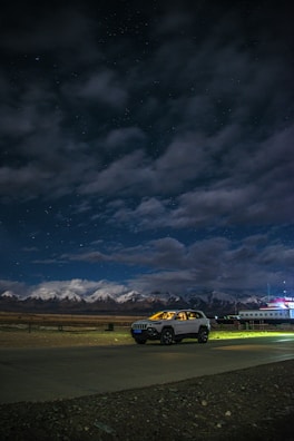 Evening view of a taxi parked near a cozy Himachal village under a starry sky.