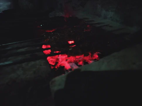 Warm, glowing embers of the traditional pampa grill fire with flames licking the coals.