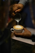 Close-up of hands crafting latte art with steady attention