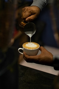 Barista carefully preparing a coffee drink with latte art on top.
