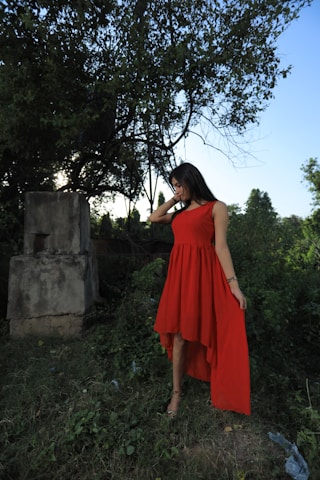 A stylish woman wearing a flowing dress in a serene outdoor setting.