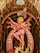 A statue of a multi-armed goddess adorned with intricate patterns and vibrant colors. The figure is posed gracefully, with one leg raised and appears to be standing atop a defeated figure. The setting includes a decorative arch and is richly detailed.