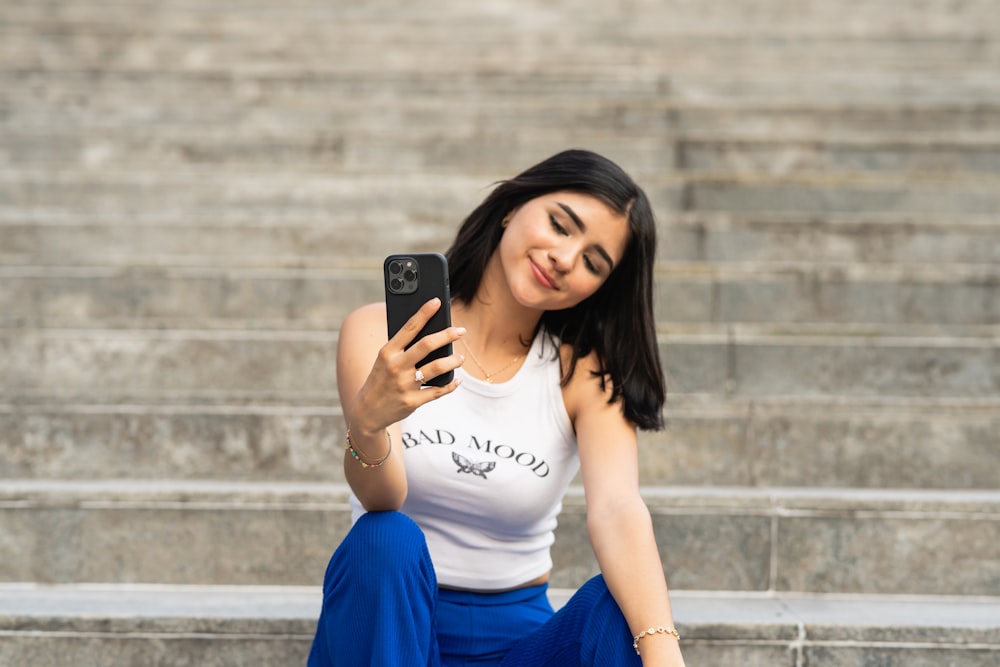 a woman sitting on the steps looking at her cell phone