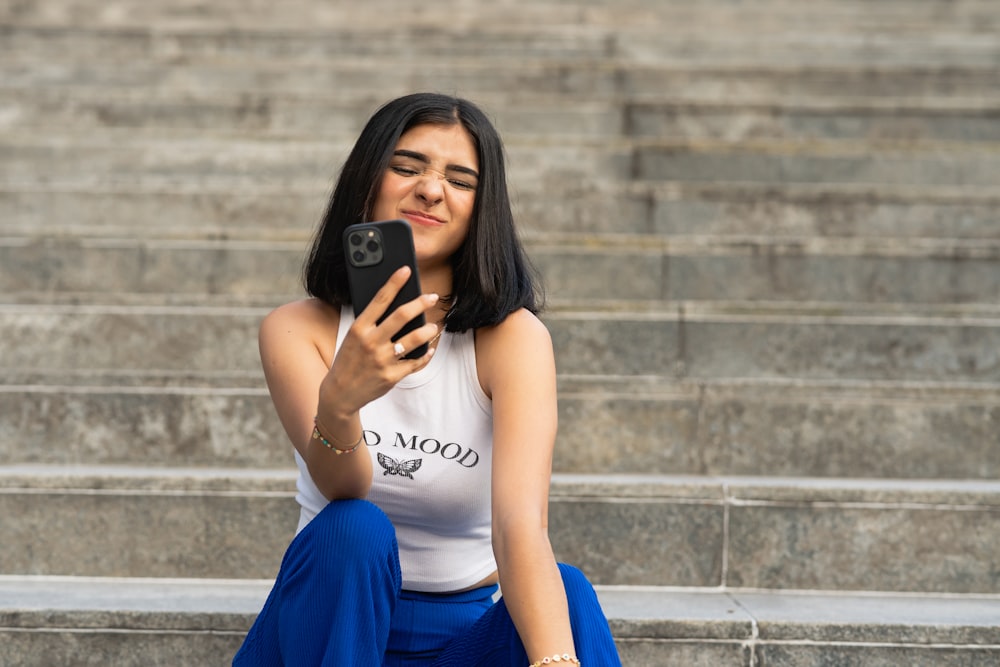 a woman sitting on steps looking at her cell phone