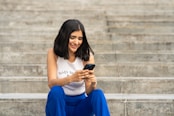 a woman sitting on steps looking at her cell phone