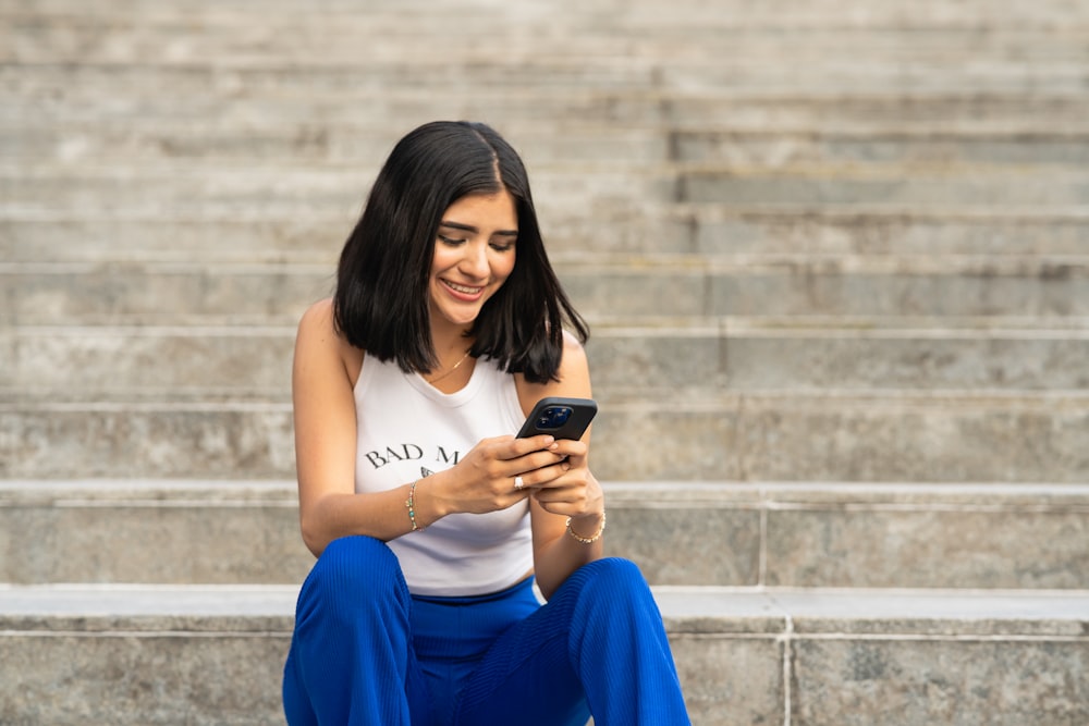 a woman sitting on steps looking at her cell phone
