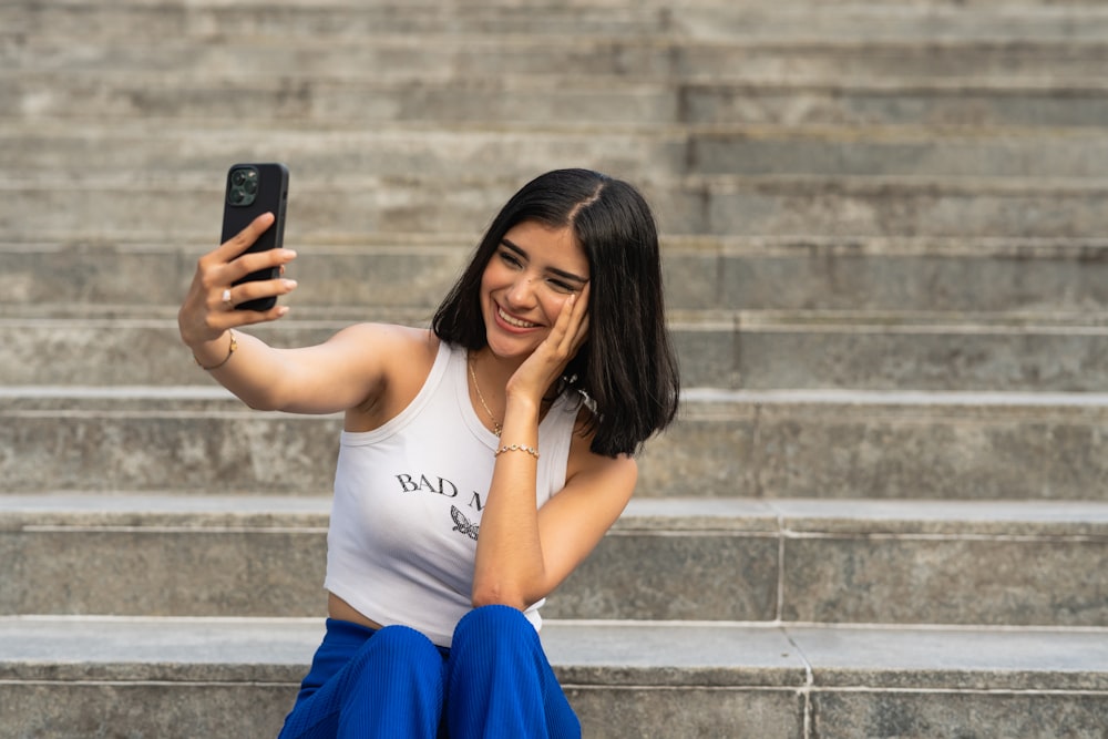 a woman sitting on steps taking a picture with her cell phone