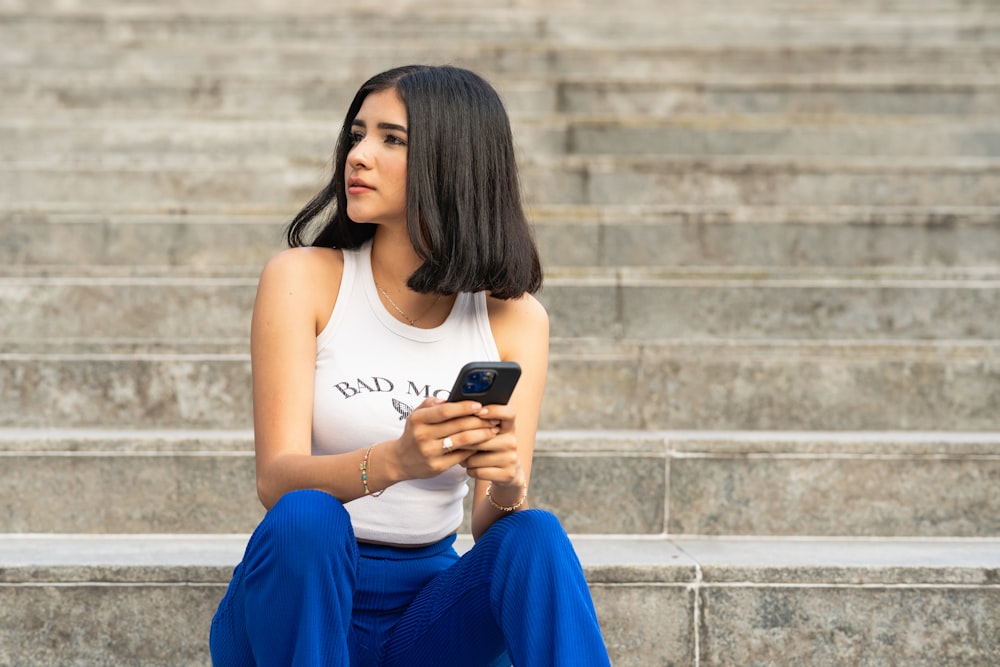 a woman sitting on steps looking at her cell phone
