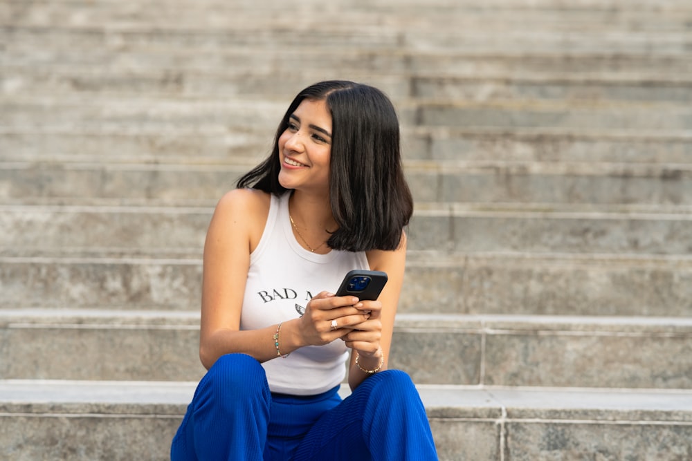 a woman sitting on steps looking at her cell phone