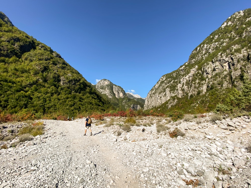 a person walking down a dirt road in the mountains