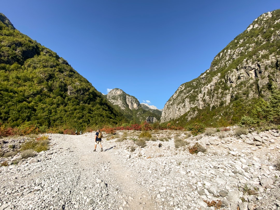 a person walking down a dirt road in the mountains, In the Albanian Alps