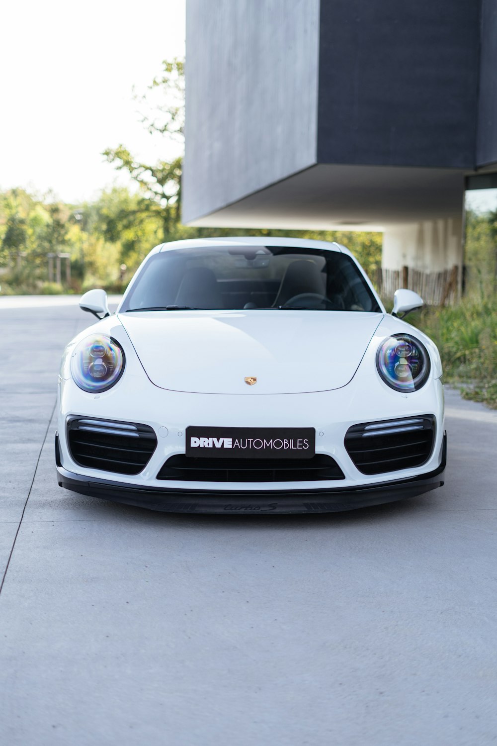 um carro esportivo branco estacionado em frente a um prédio