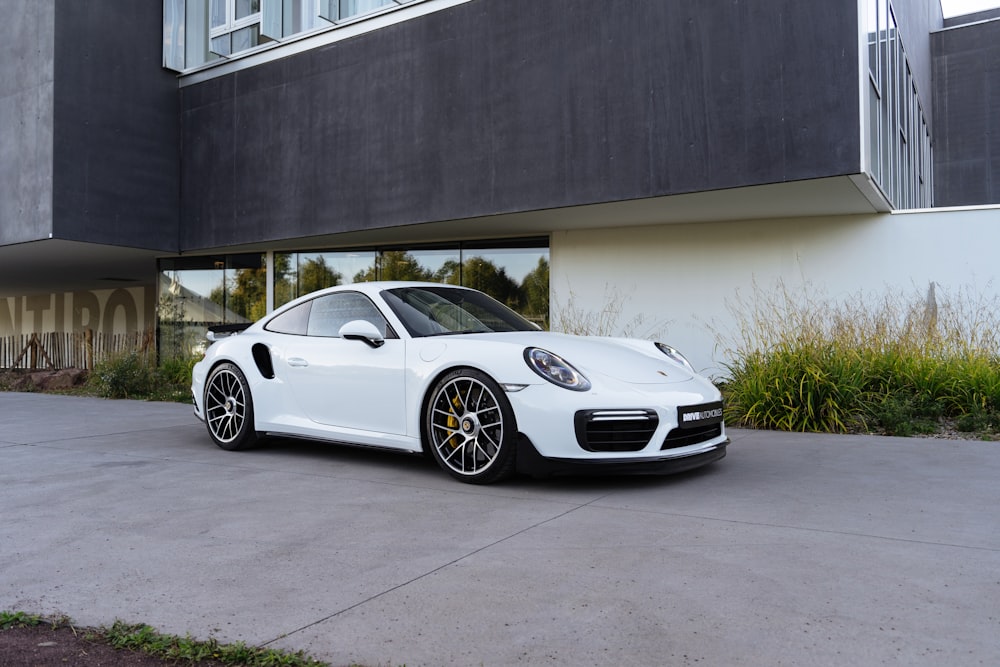 Um Porsche branco estacionado em frente a um prédio