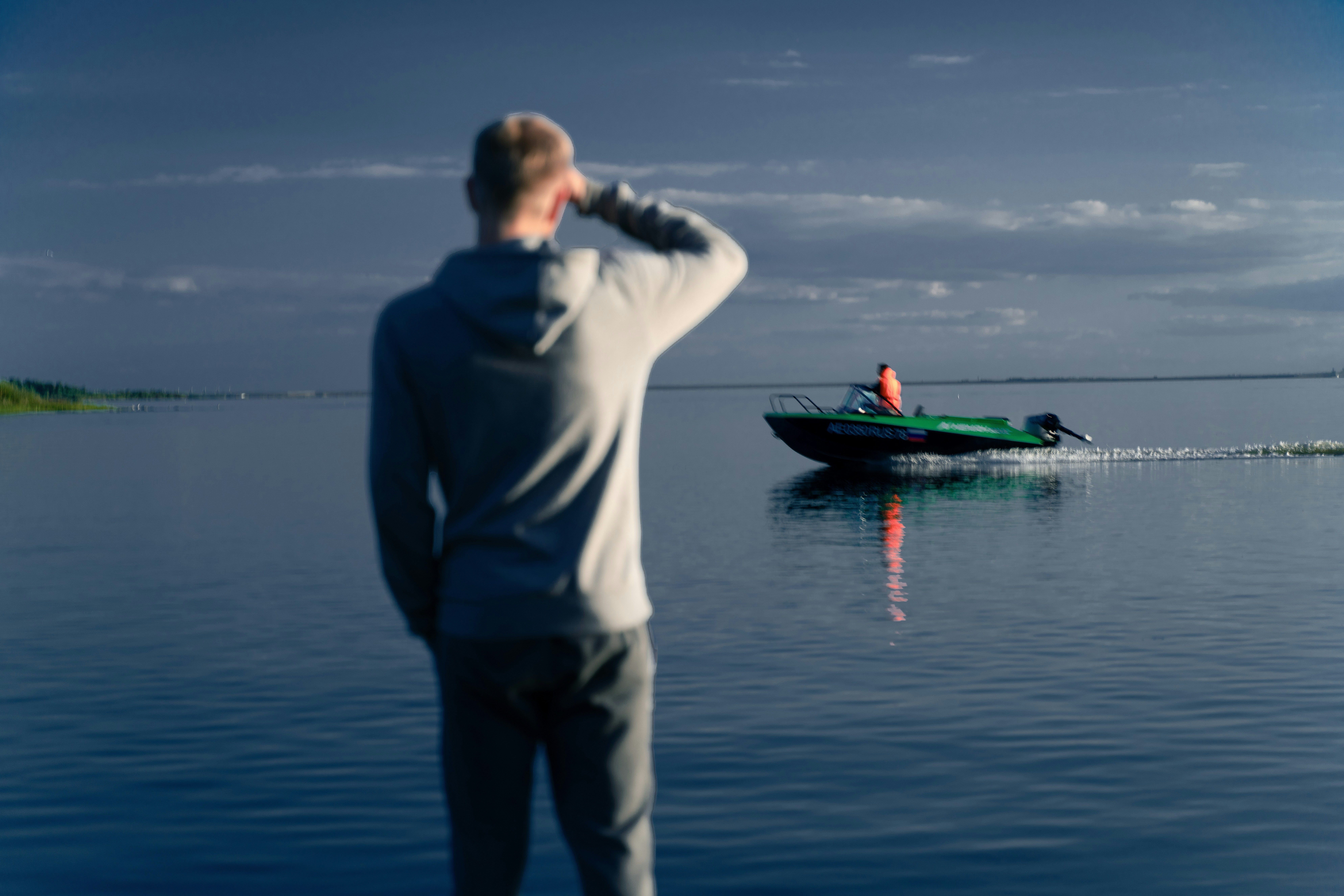 um homem parado em frente a um barco em um lago