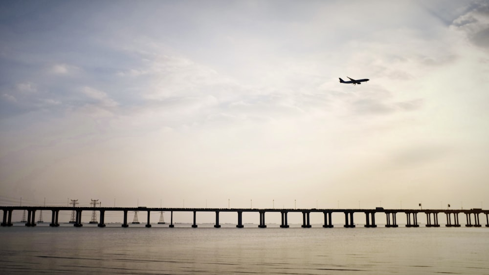 an airplane is flying over a large bridge