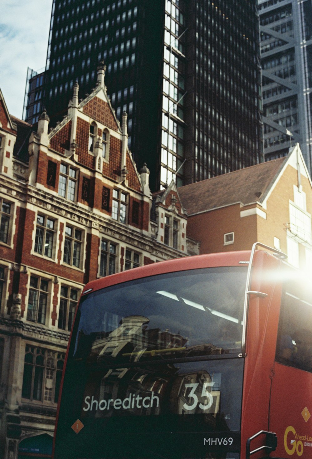 Un autobús rojo circulando por una calle junto a edificios altos