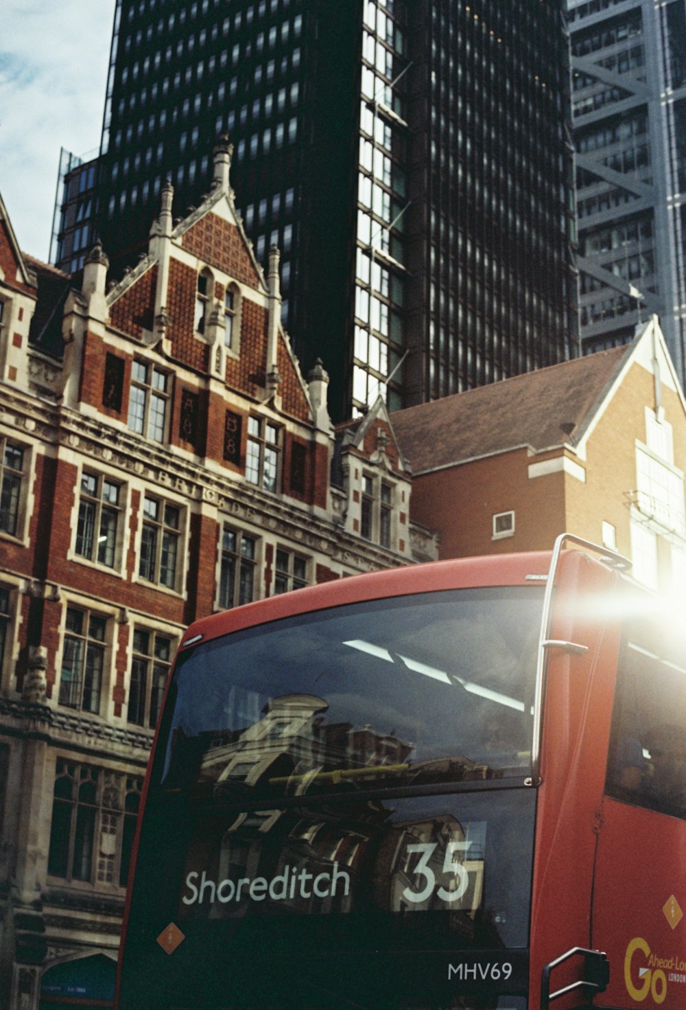 a red bus driving down a street next to tall buildings