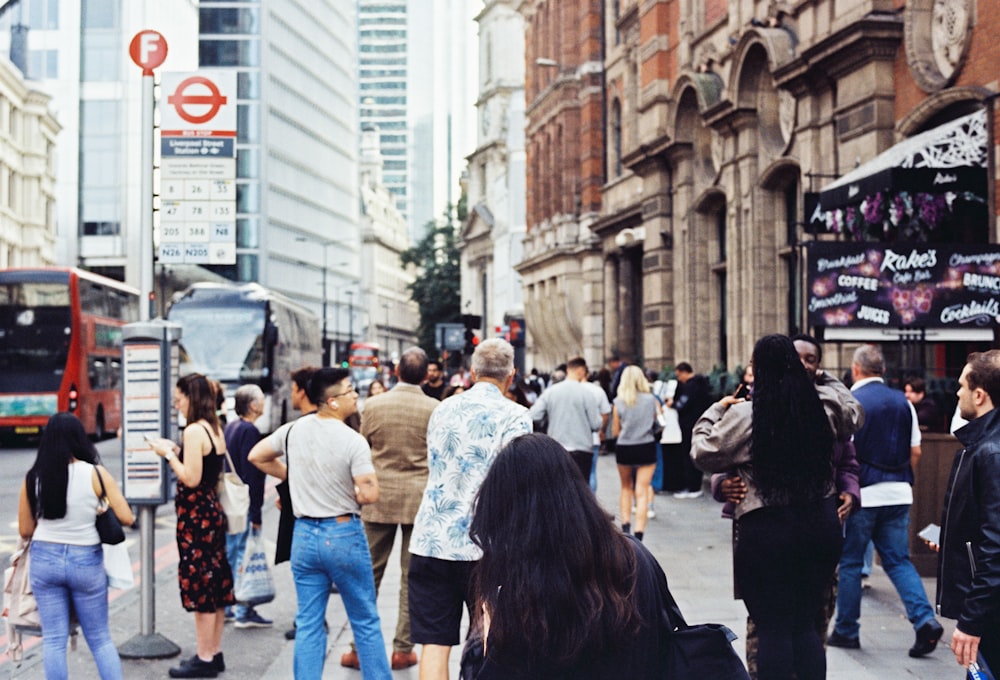 a crowd of people walking down a street next to tall buildings