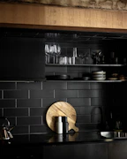 A sleek kitchen setup with green ceramic dishes and wooden utensils neatly arranged on a countertop.