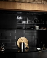 a black kitchen with a wooden cutting board on the counter