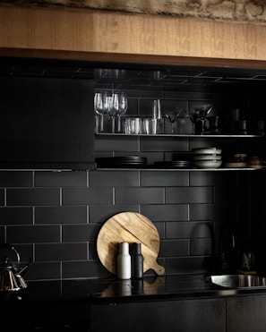 a black kitchen with a wooden cutting board on the counter