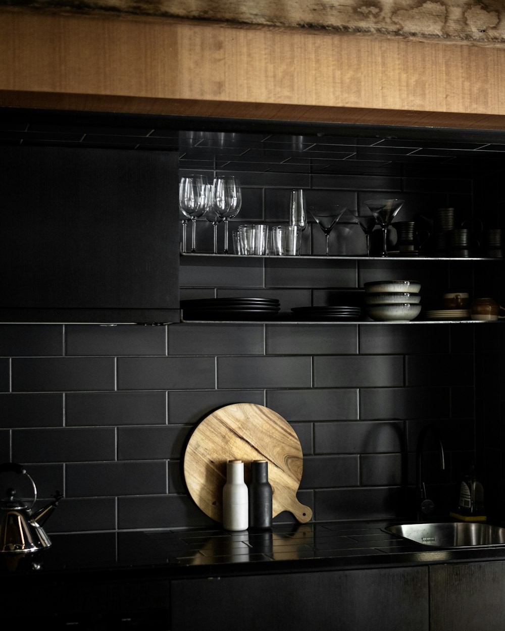 a black kitchen with a wooden cutting board on the counter