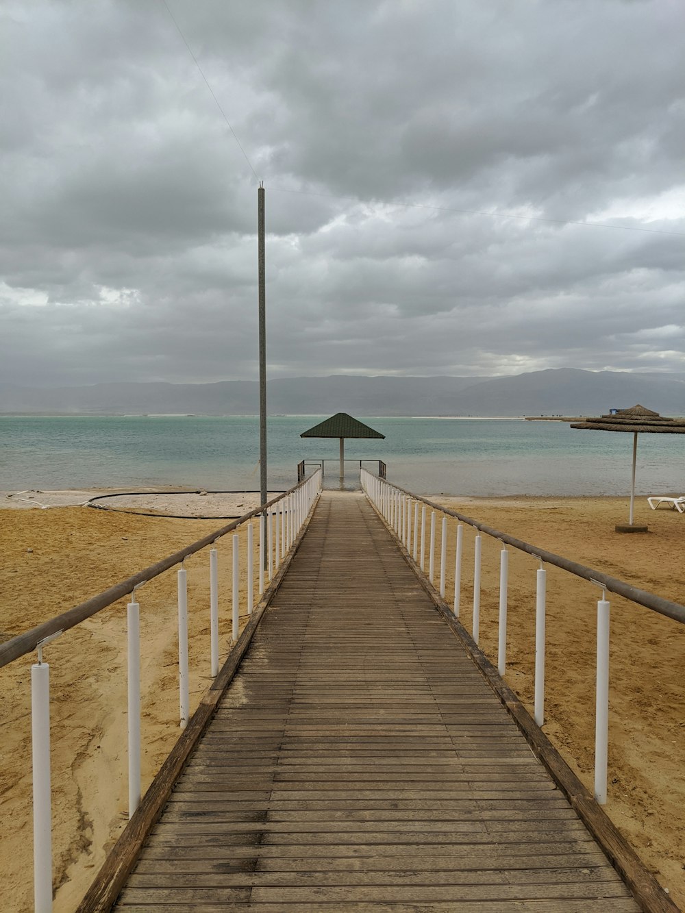 a wooden walkway leading to a beach with an umbrella