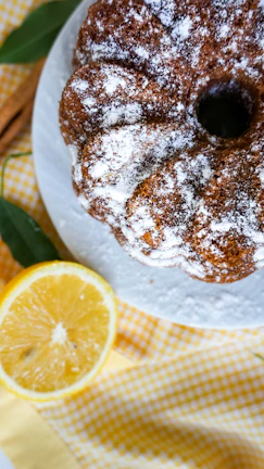 Elegant vanilla bundt cake sprinkled with powdered sugar and cinnamon sticks.