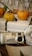 A digital camera labeled 'Himpex DigiArt 660' rests on a stack of books. Two small pumpkins are nearby, along with a decorative paper flower made from printed text. The books include titles like 'Notre Dame’in Kamburu' by Hugo.
