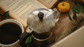 A warm beige background with a vintage coffee grinder and a classic leather-bound book