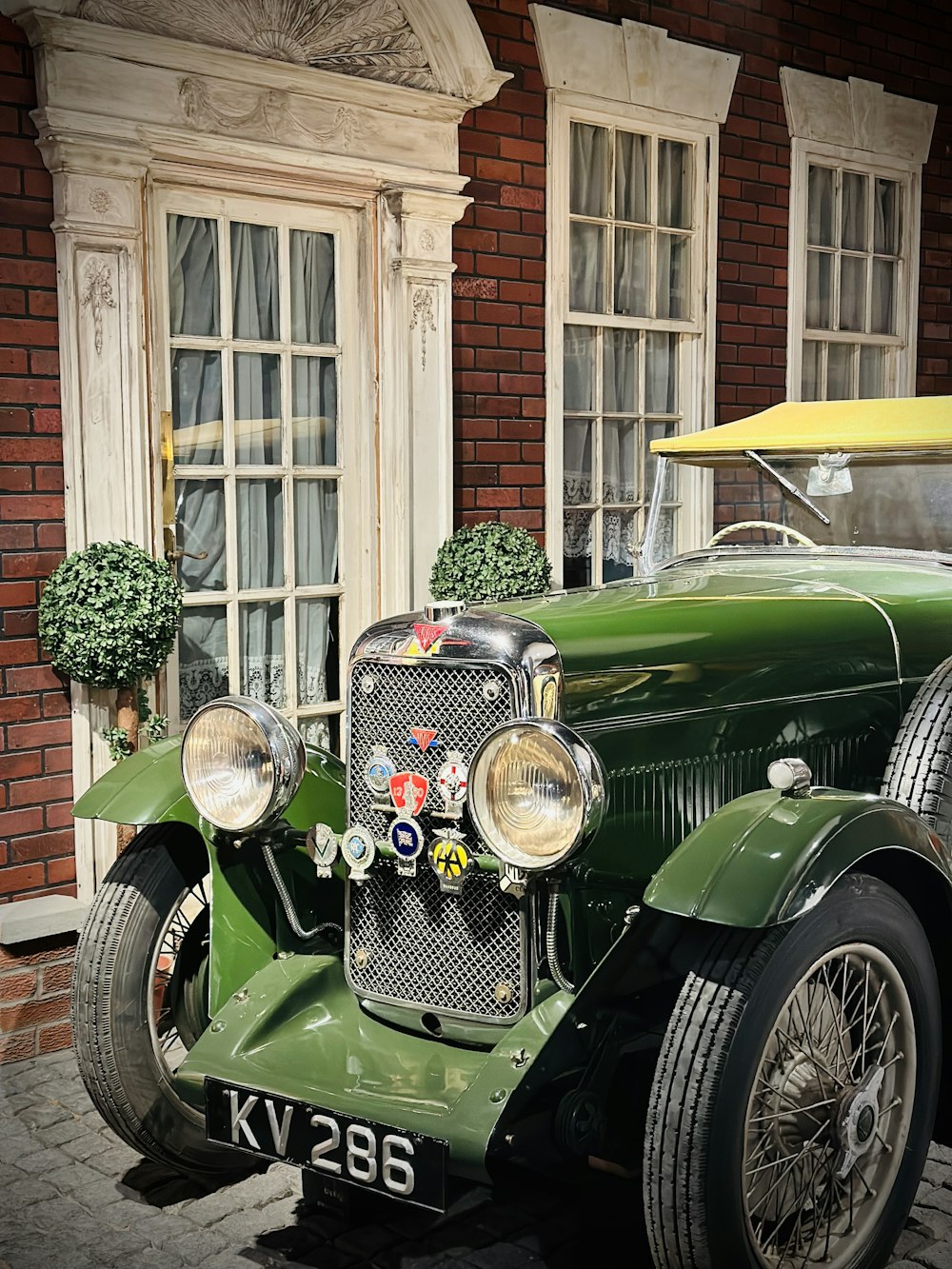 an old green car parked in front of a building