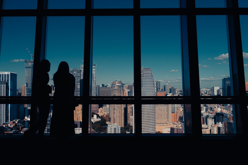 a couple of people standing in front of a window