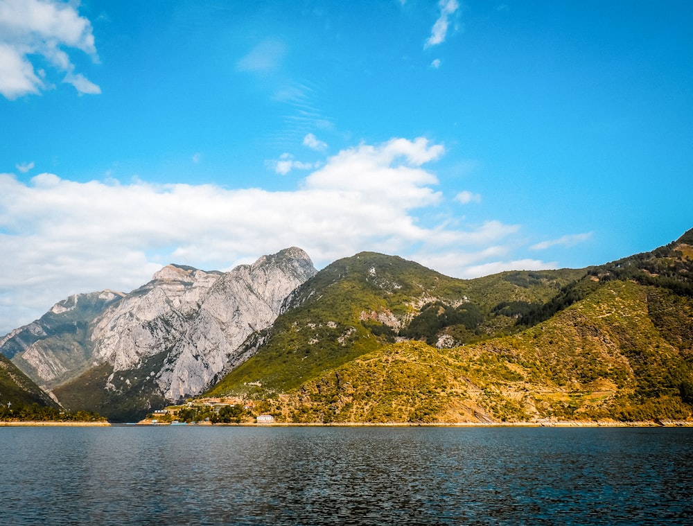 a body of water surrounded by mountains under a blue sky