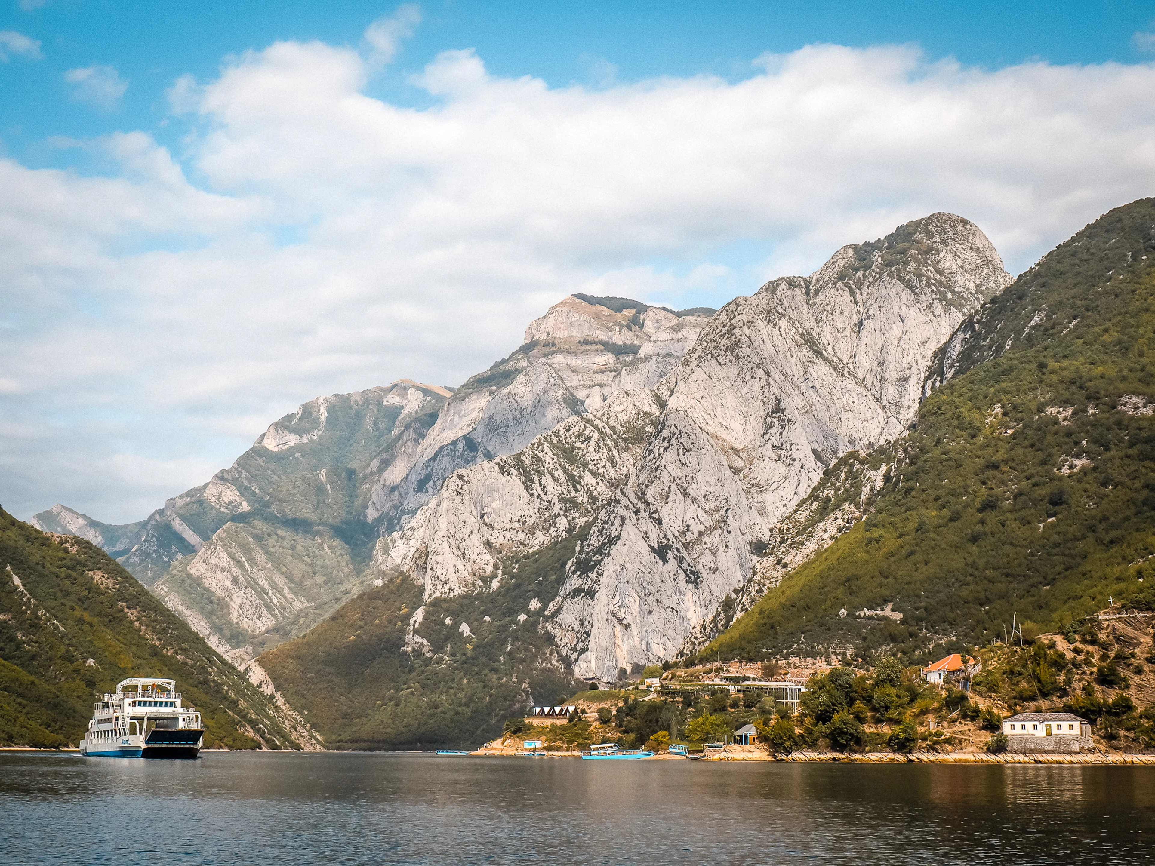 A ferry on Lake Koman between steep grey mountain walls