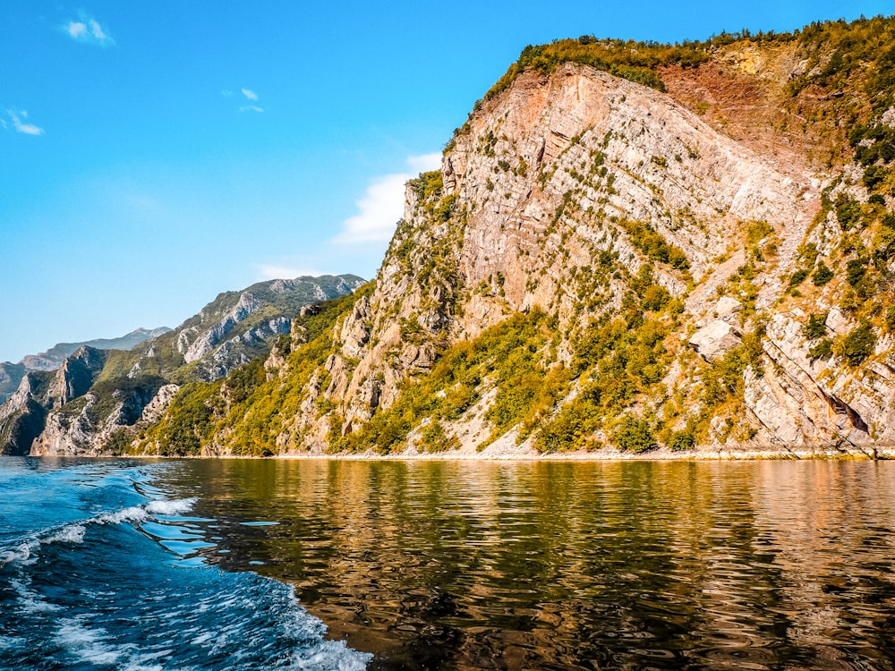 a boat traveling on a body of water near a mountain