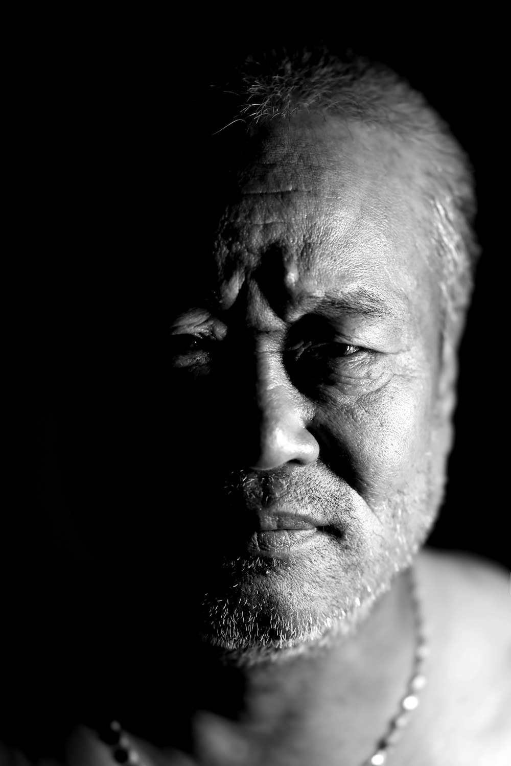 a black and white photo of a man wearing a necklace