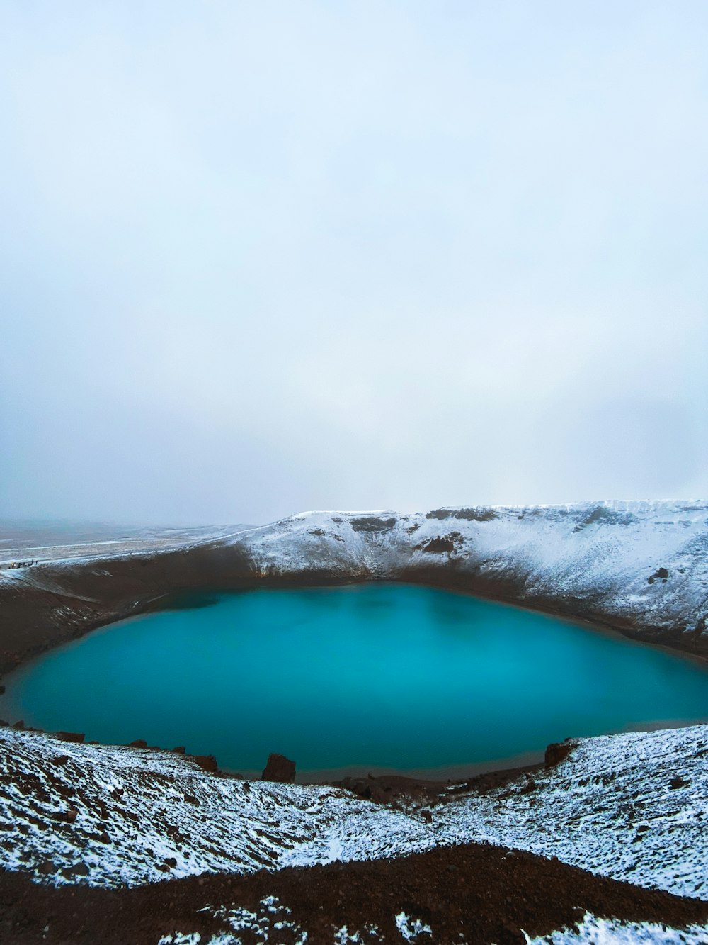 a blue lake surrounded by snow covered hills