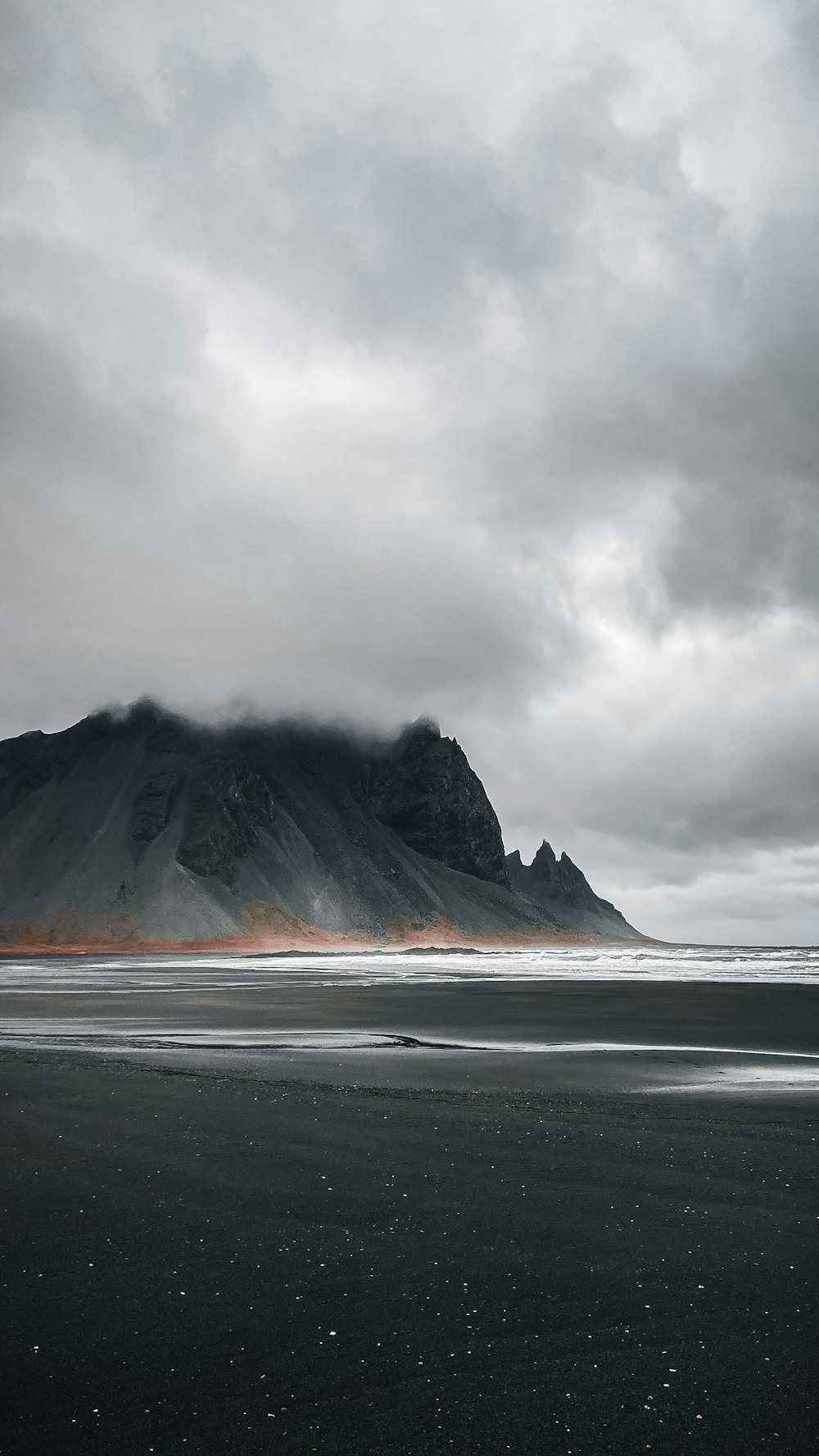 a black sand beach with a mountain in the background