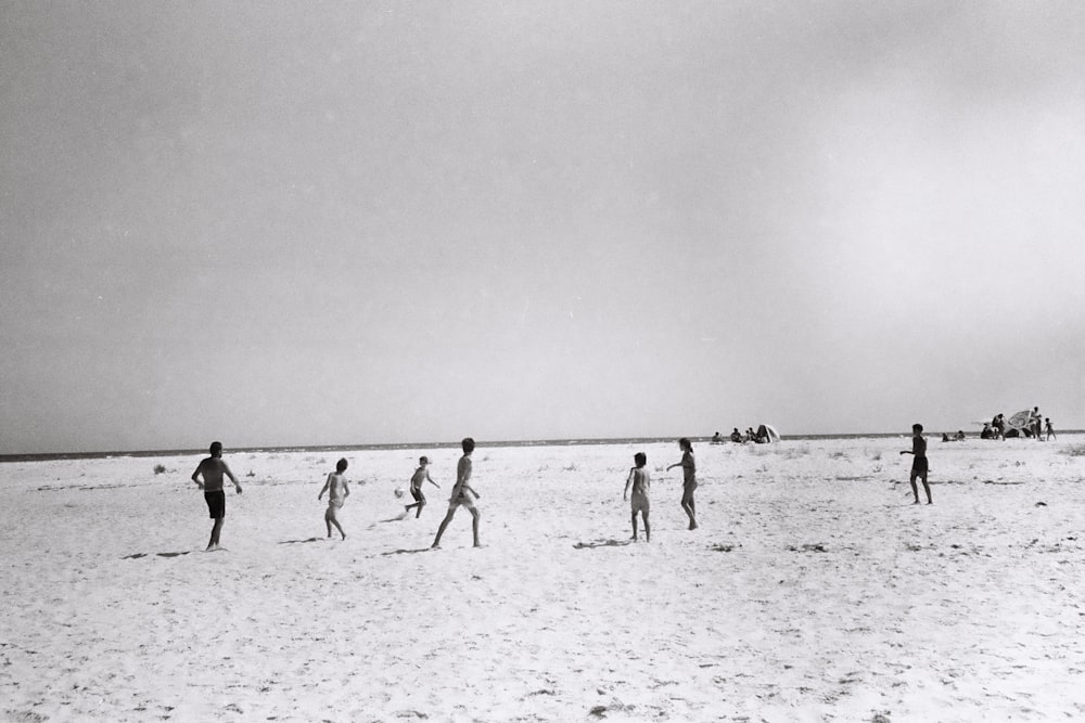 a group of people standing on top of a sandy beach