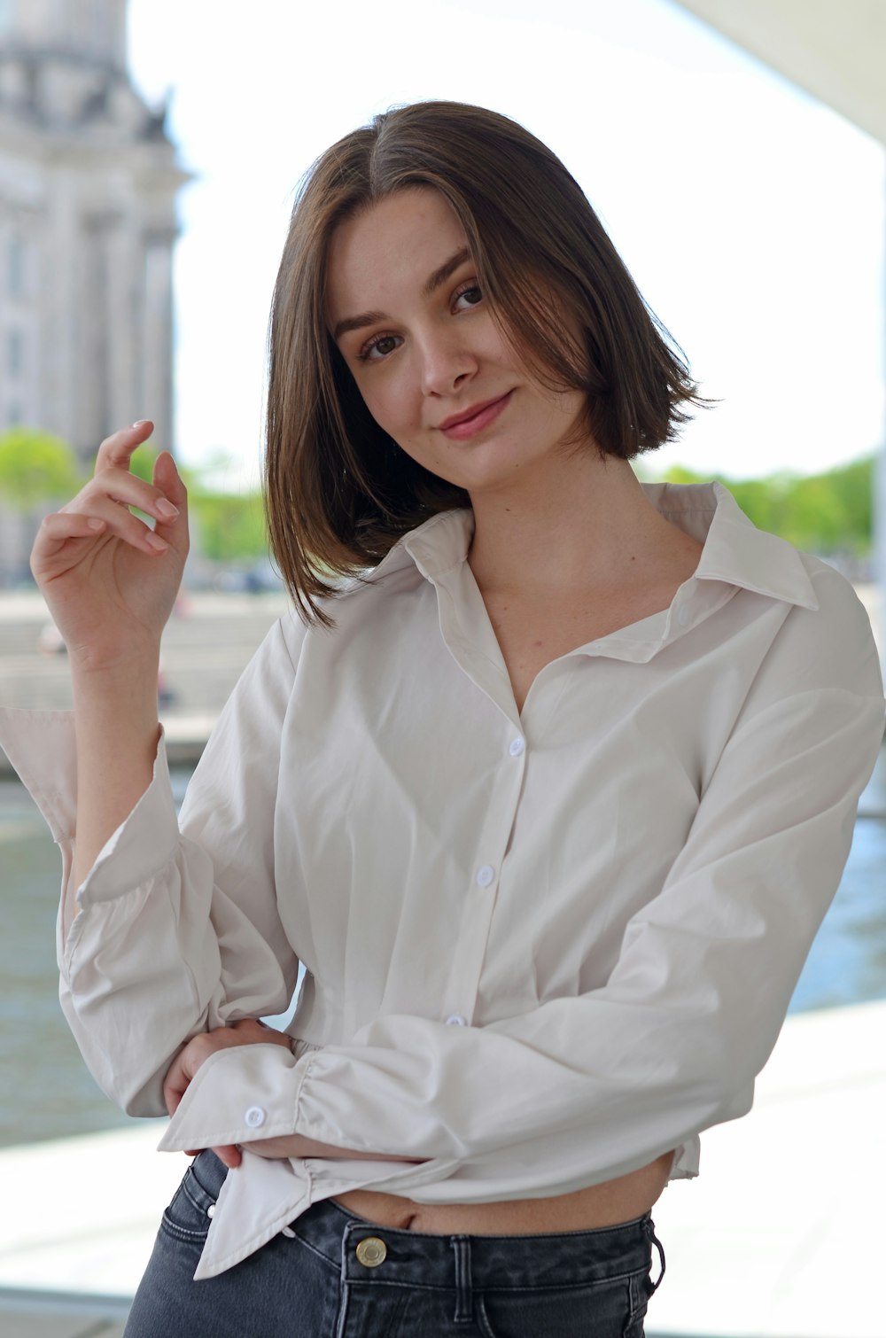 a woman in a white shirt is holding a cigarette
