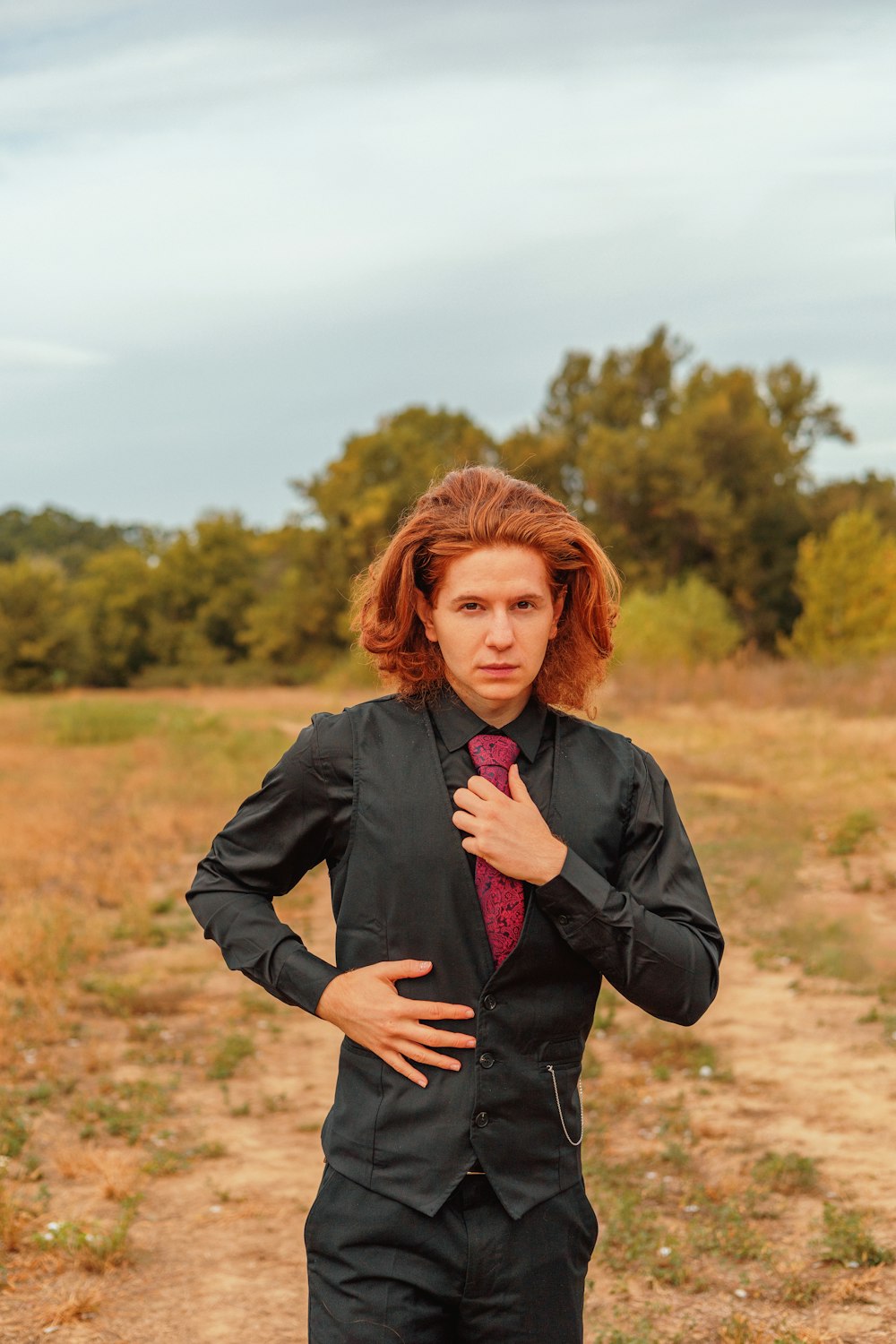 a man in a suit and tie standing in a field