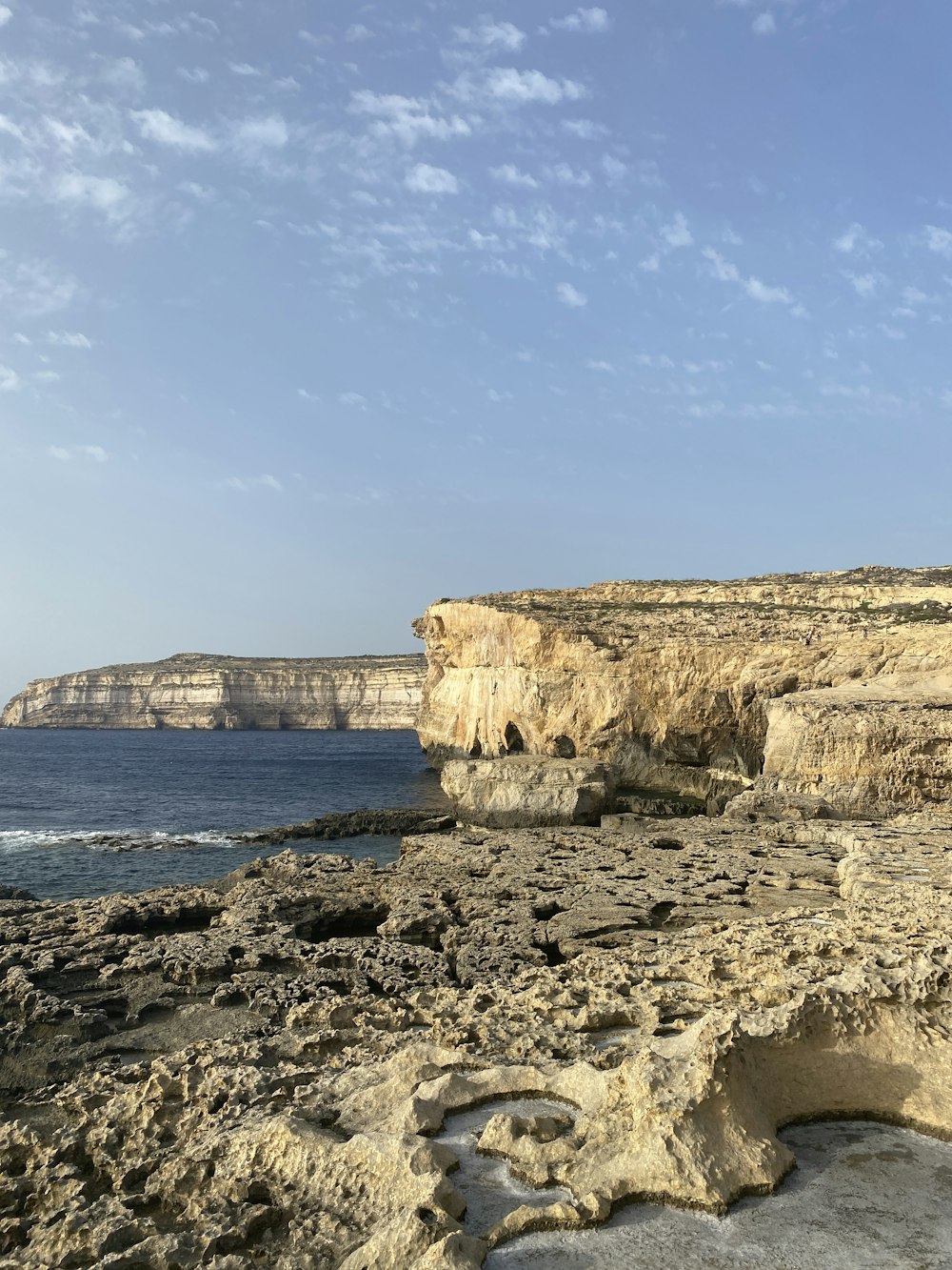 a rocky beach next to the ocean under a blue sky