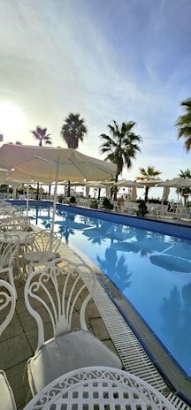 Inviting outdoor terrace with ivory and gold decor overlooking a sparkling pool at sunset.