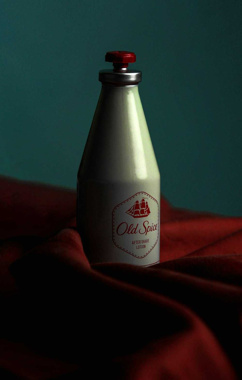a bottle of old spice sitting on a red cloth