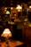 A dimly lit antique shop with various vintage objects, including lamps with stained glass and colored shades. Shelves are filled with decorative items and furniture, creating a nostalgic and cozy atmosphere.