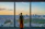 Smiling businesswoman standing by a window overlooking a global city skyline at dusk.