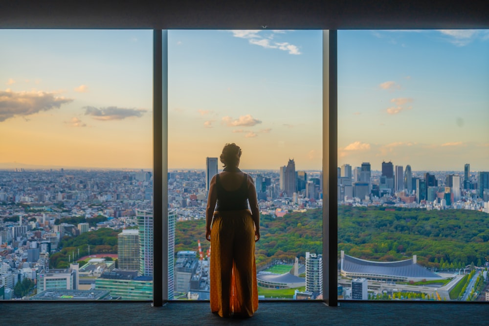 uma mulher em frente a uma janela com vista para uma cidade
