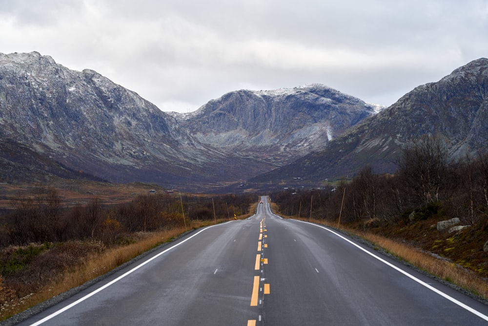 an empty road with mountains in the background