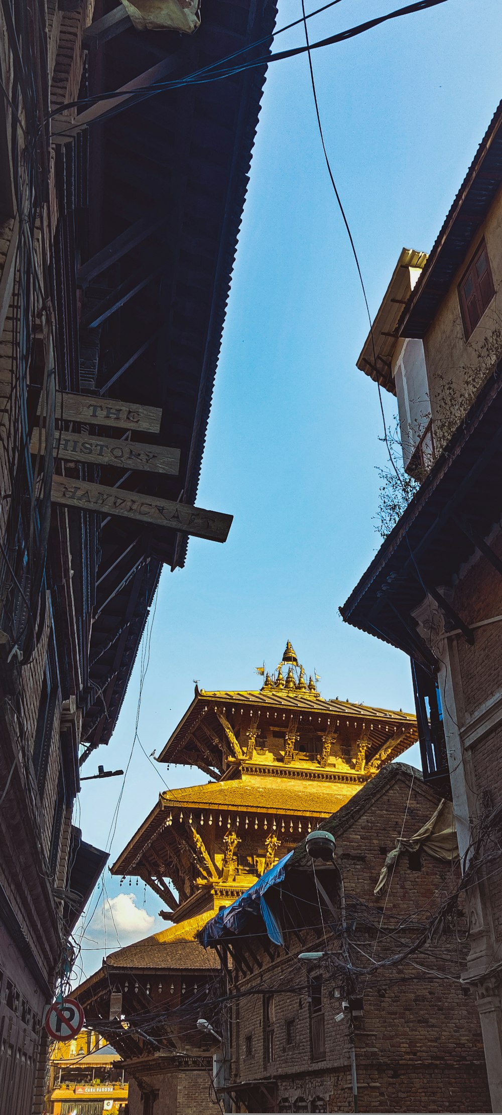 a narrow street with a yellow building in the background